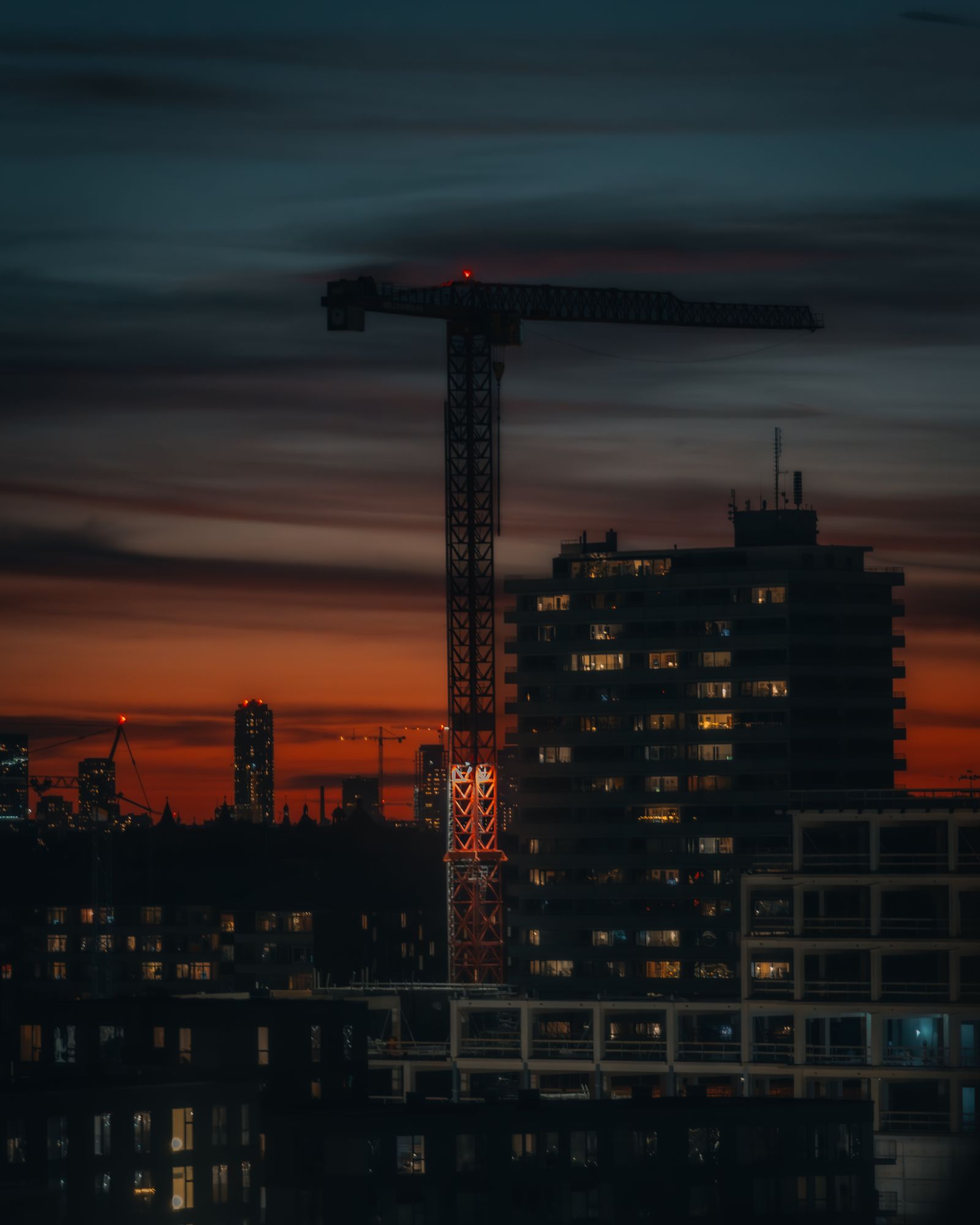 An urban construction site and crane at sunset